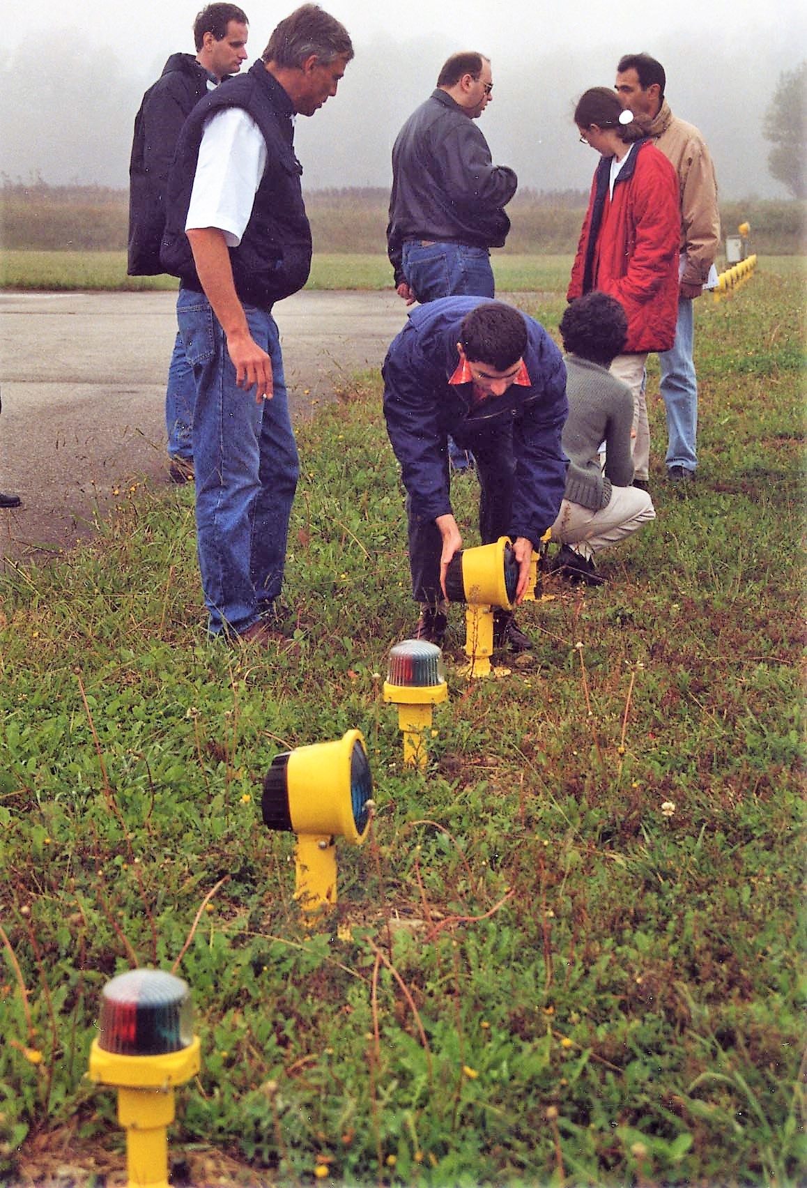 Éric fait le tour de la piste avec un groupe de stagiaires à la Toussaint en 2002. Un groupe de cinq stagiaires observent Eric donner des instructions à un sixième penché sur les différentes lampes de repérage de piste au sol