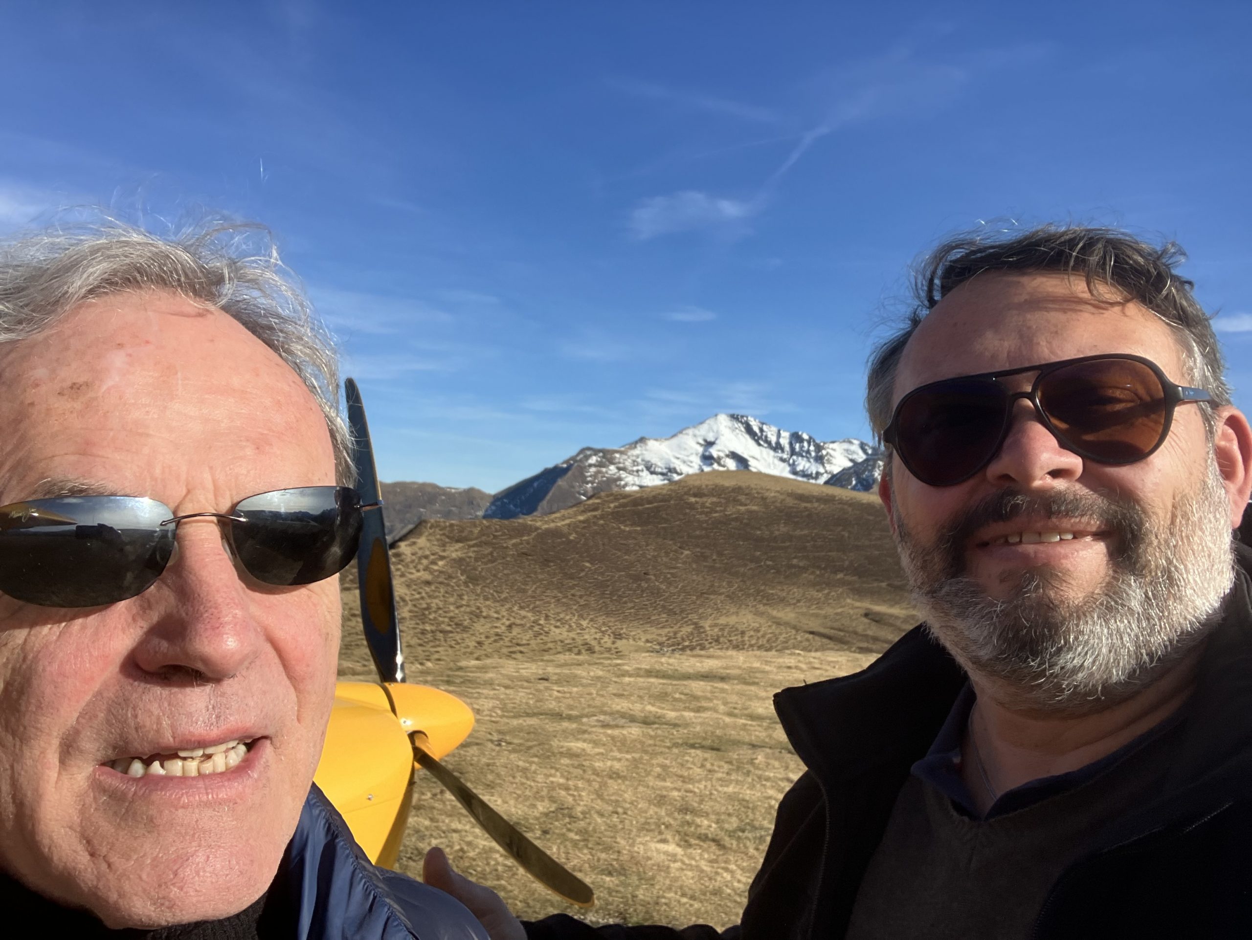 Selfie de Jean-Claude et Martial, avec en fond l'hélice de l'avion et la montagne à Hautacam sur ciel bleu dégagé.